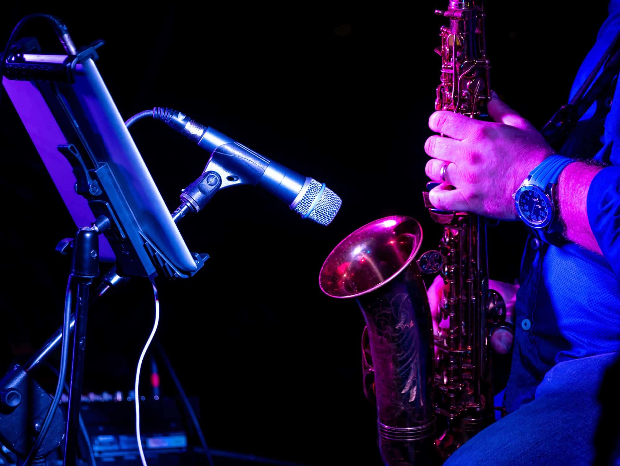Man playing saxophone next to a microphone