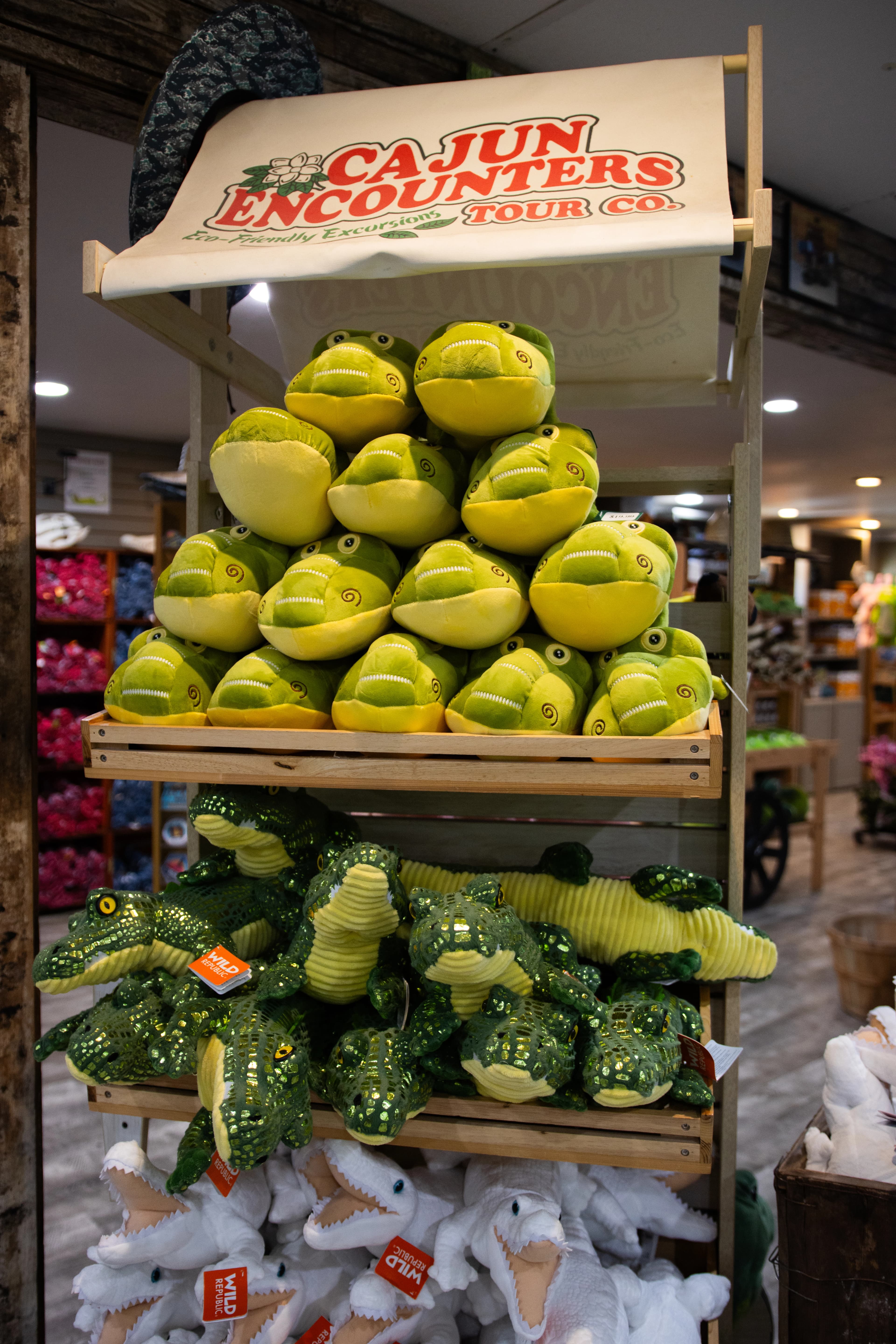 A display of swamp-themed plush toys for sale in a gift shop.
