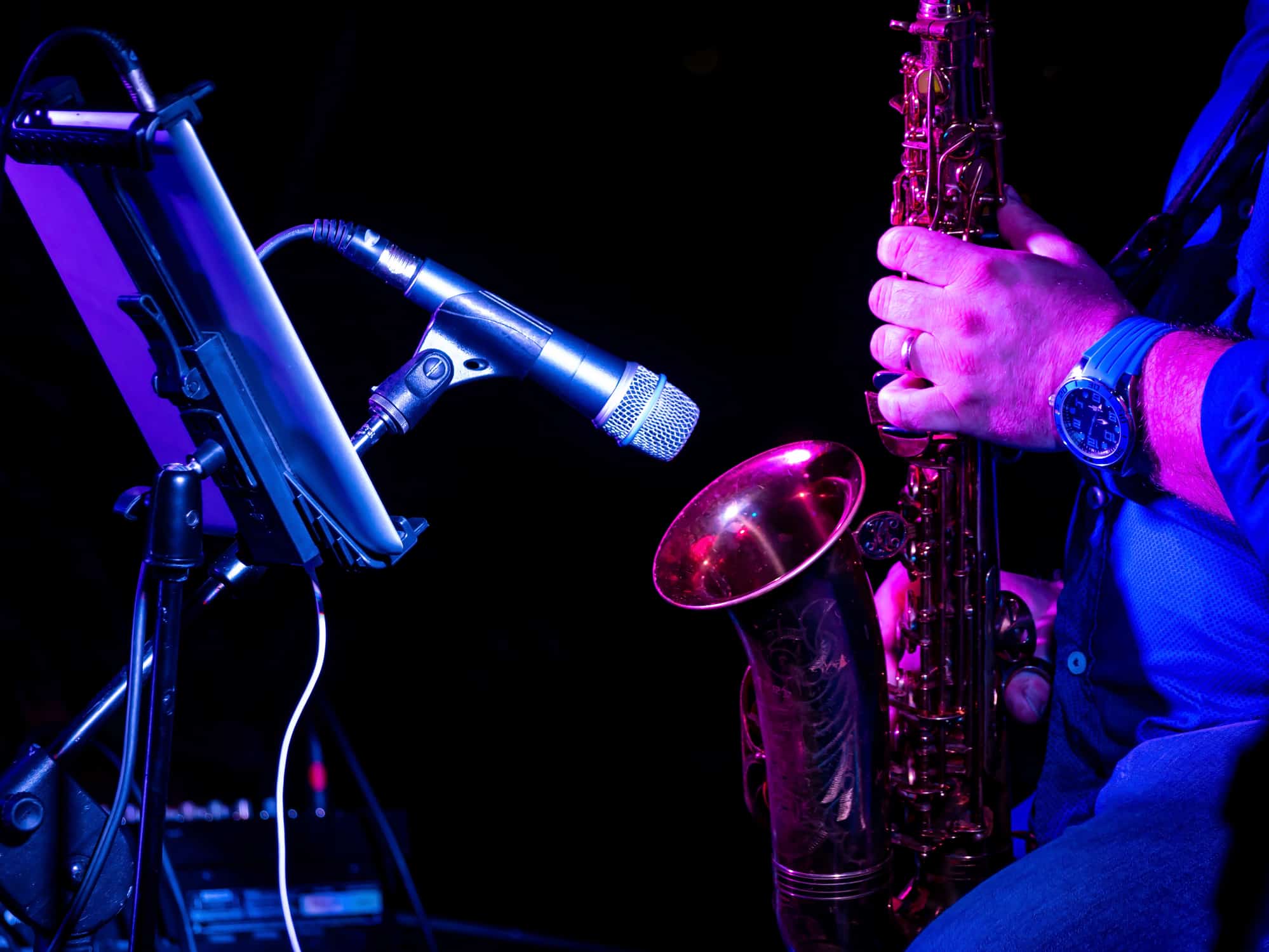 Man playing saxophone next to a microphone