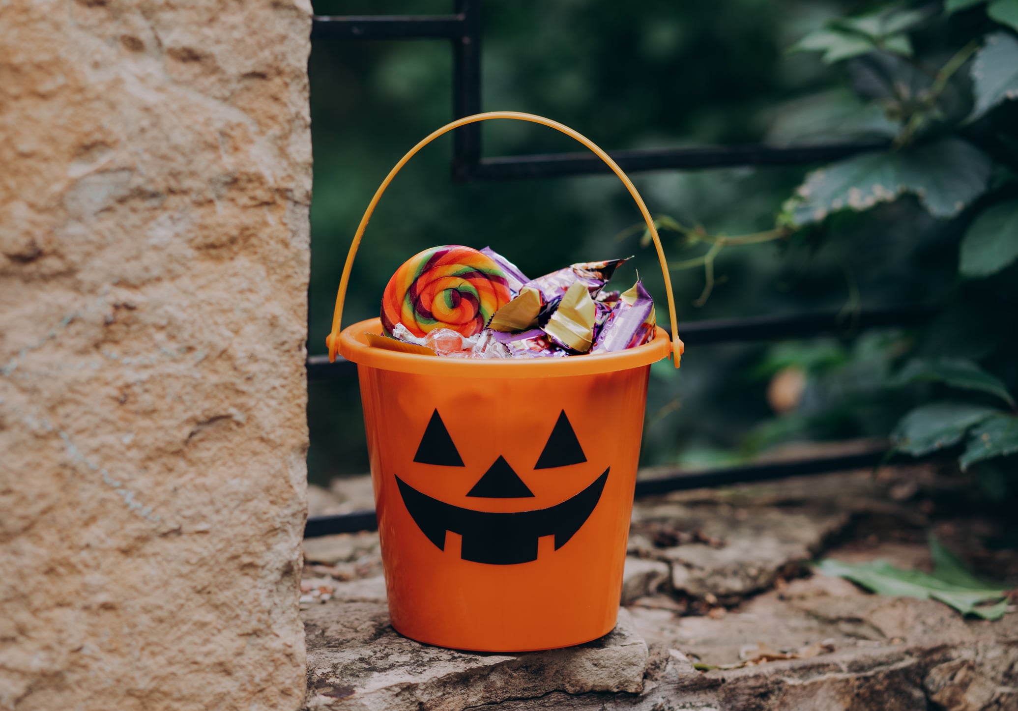 trick-or-treating spots with a Jack o Lantern orange bucket with candy on the street