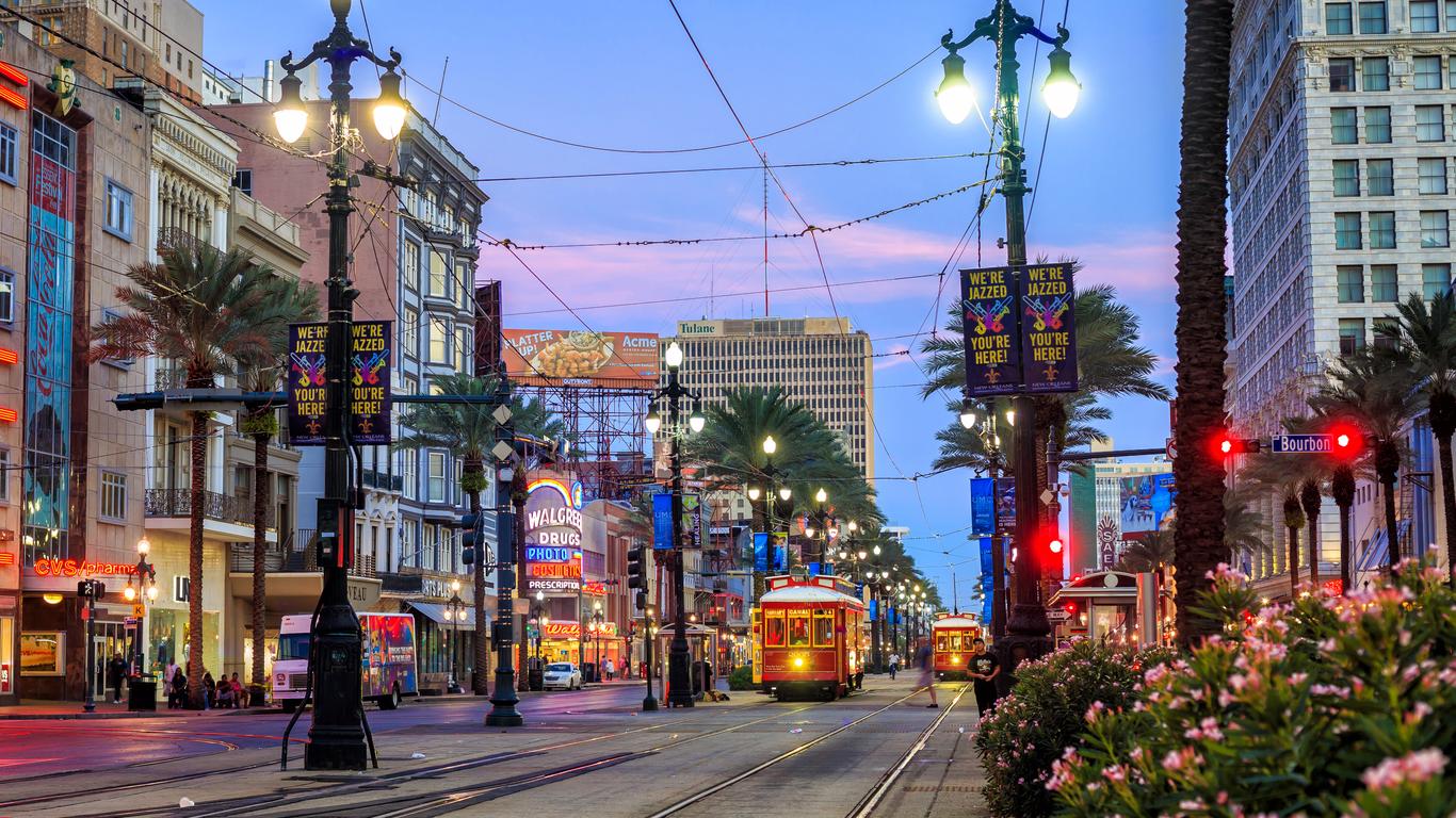 The city of New Orleans in June, featuring a streetcar, traffic lights, and a sunset.