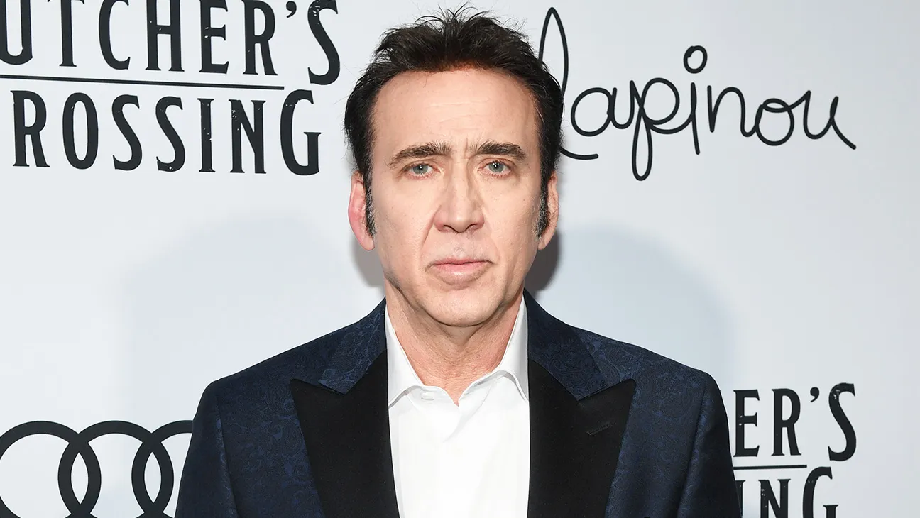 Nicholas Cage standing in front of a white backdrop.